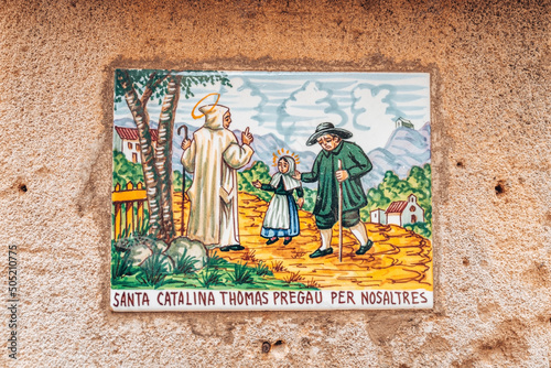 Painted tile with text. Close-up of textured wall of old building. Concept of art in structures at historic town.