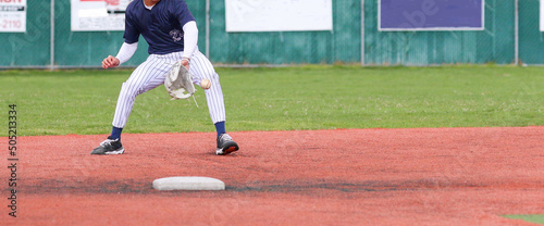 Baseball second baseman backhanding a ground ball during a game photo