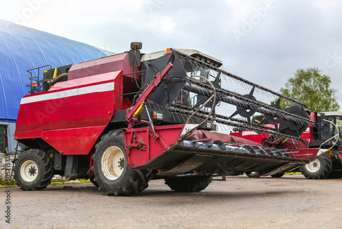 The combine stands on a platform for agricultural machinery, near the barn.