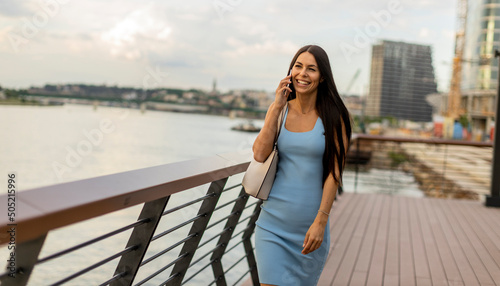 Young woman using a mobile phone while walking on the river promenade