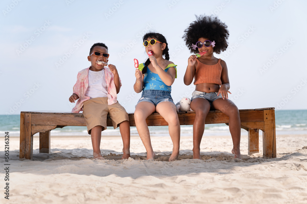 Happy fun boy and girl kids eat ice cream on the beach - obrazy, fototapety, plakaty 