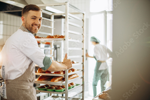 Man baker at the kitchen by the pastry cart