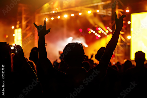 Men and women with raised hands at a concert event.