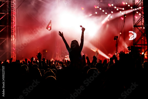 People dancing and having fun at summer festival party outdoor - Crowd with hands up celebrating concert event. photo