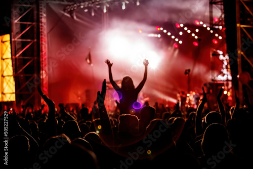 Men and women with raised hands at a concert event.