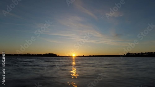 Time lapse of sunset over lake with orange blue sky
