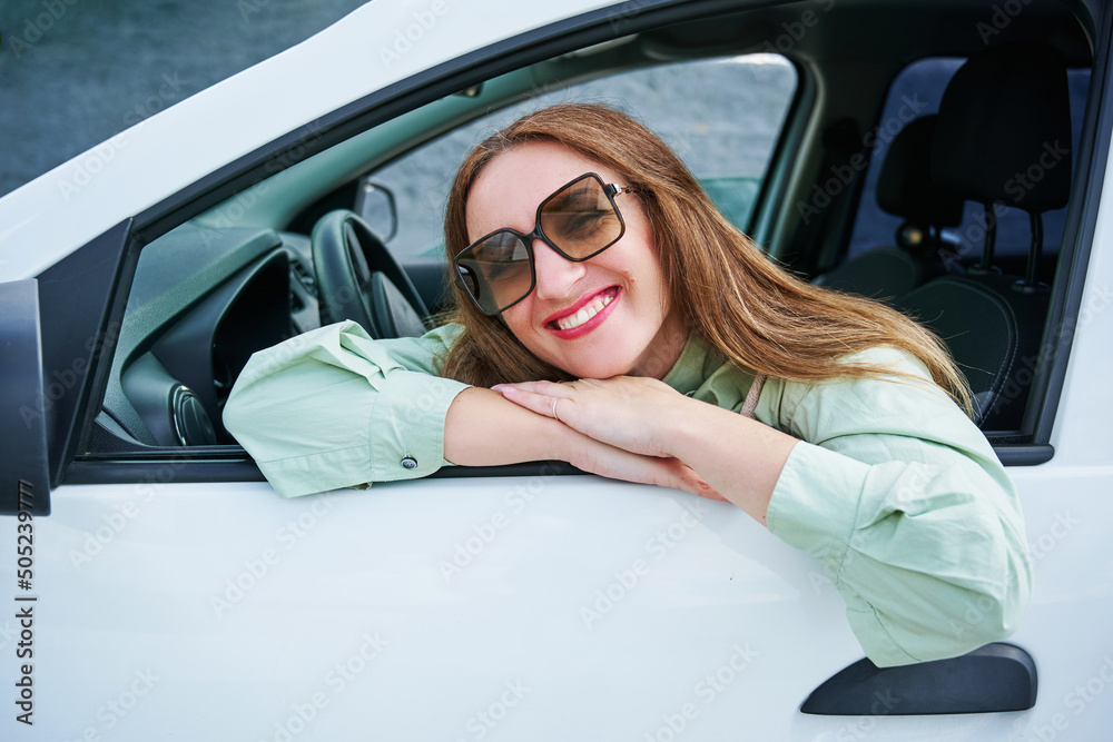 Happy young woman enjoys buying a new car or a rental car. The concept of buying a new car, renting and freedom of movement
