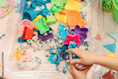 kinetic sand. children's hands play with multi-colored polymer sand.