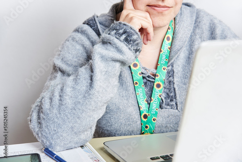 Person studies or works using a sunflower lanyard, invisible disabilities symbol photo