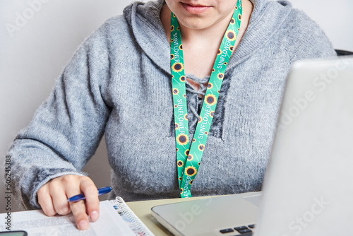 Woman studies or works at home using a sunflower lanyard, invisible disabilities photo