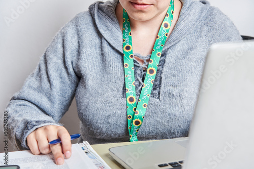 Woman studies or works at home using a sunflower lanyard, invisible disabilities
