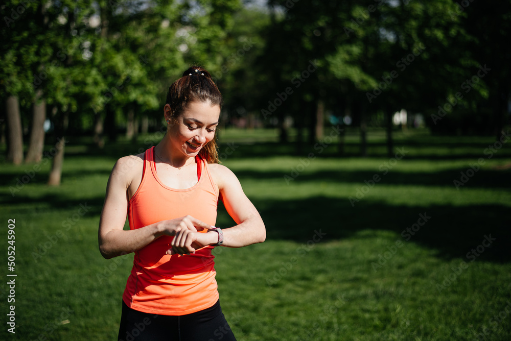 The girl uses a fitness bracelet while running The girl uses a fitness bracelet while running