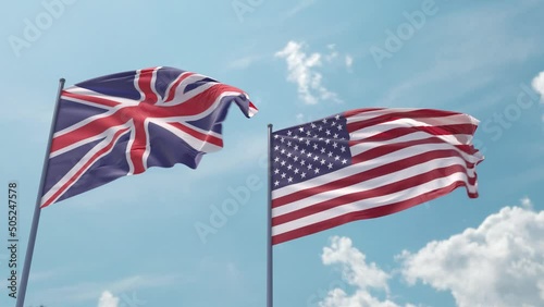 UK and USA flag on flagpole fluttering fast in strong wind in blue sky