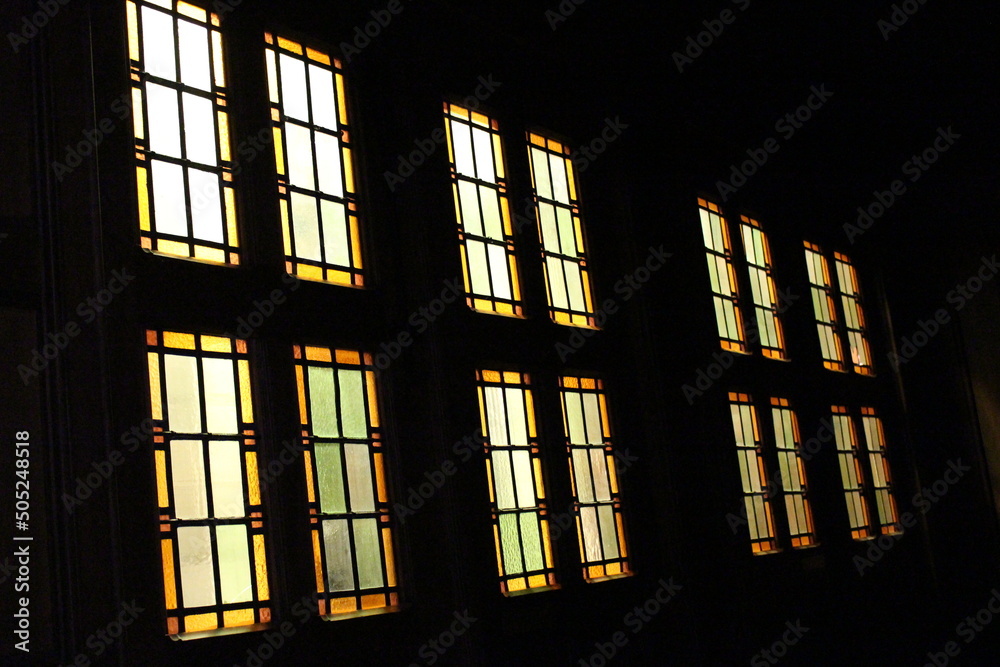 row of yellowish stained glass windows against black row of yellowish stained glass windows against black
