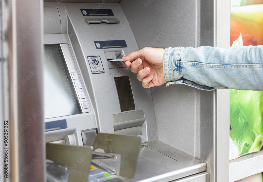 Male hand inserting ATM card into ATM bank machine Male hand inserting ATM card into ATM bank machine