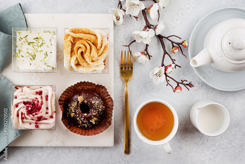 Drinking afternoon tea with sweet desserts. Plate with different pieces of cakes on table. Pastry, bakery, confectionery concept