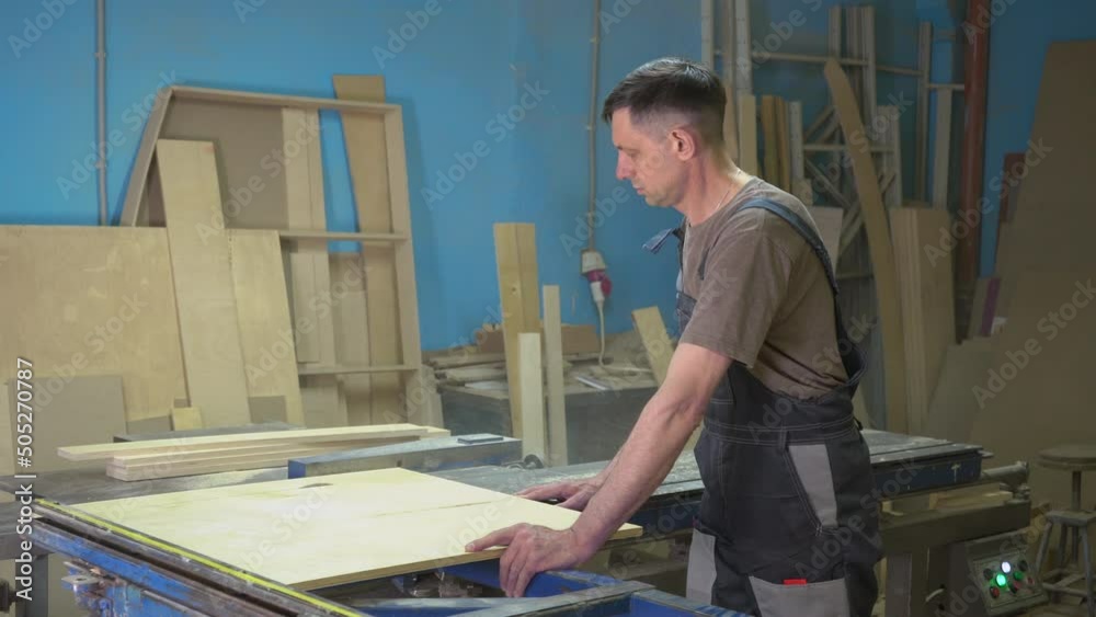 A carpenter cuts wood on a circular saw in a joinery. Furniture manufacture. A carpenter cuts wood on a circular saw in a joinery. Furniture manufacture.