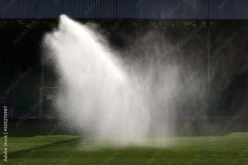 Podlewanie trawy w czasie słonecznej suszy na boisku sportowym. - obrazy, fototapety, plakaty 