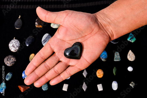 Man's hand holding a handmade black heart gem or stone. photo