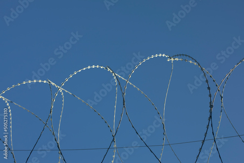 Barbed wire rings on fence. Protected area.