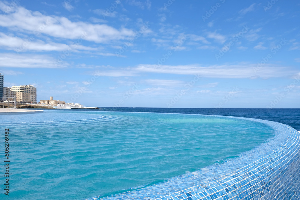 Blue clear water surface in swimming pool in a resort with sea views. Summer Vacation and rest concept. Luxury beach villa house. Blue tile mosaic pattern. Blue clear water surface in swimming pool in a resort with sea views. Summer Vacation and rest concept. Luxury beach villa house. Blue tile mosaic pattern.