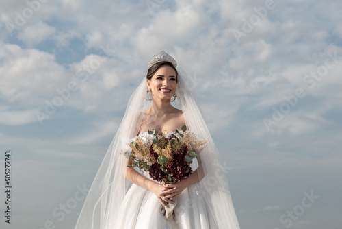 Uma jovem mulher usando um vestido de noiva com céu nublado ao fundo. photo