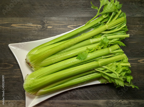 Top view of two heads of celery on a white platter.