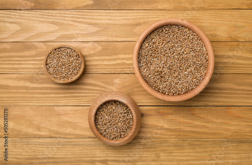 Bowls with wholegrain spelt farro on wooden background. Top view photo