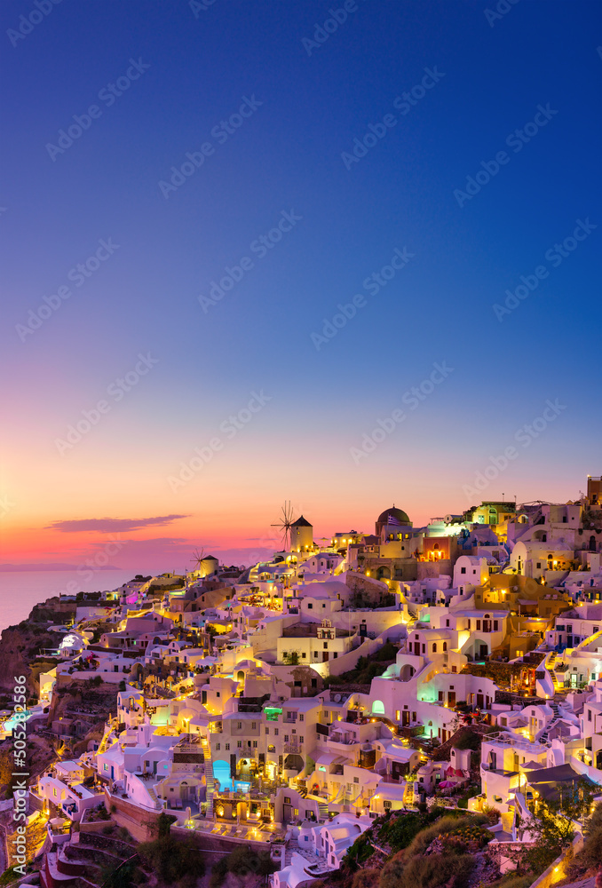 Oia village, Santorini, Greece. View of traditional houses in Santorini. Small narrow streets and rooftops of houses, churches and hotels. Landscape during sunset.