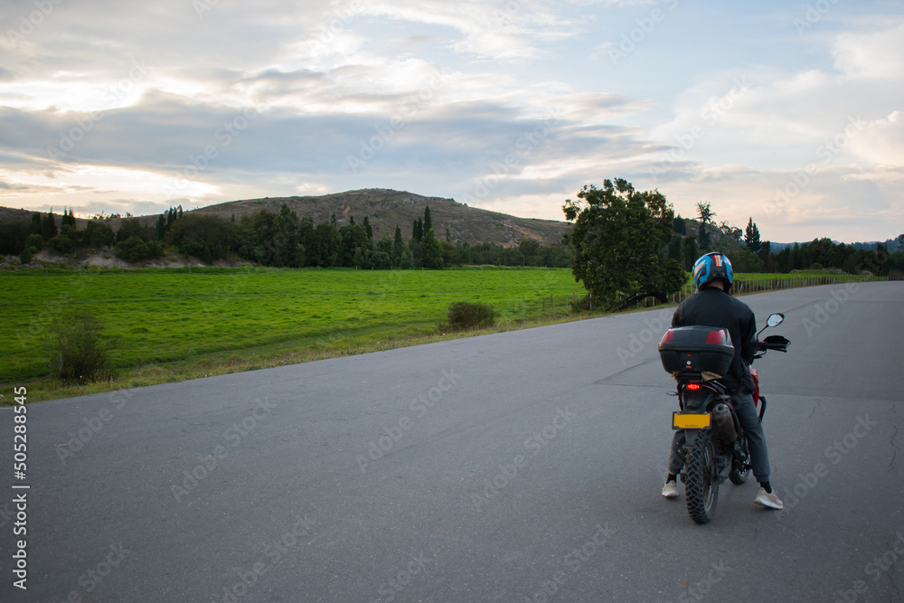 hombre conduciendo una moto con fundo de montañas y naturaleza 