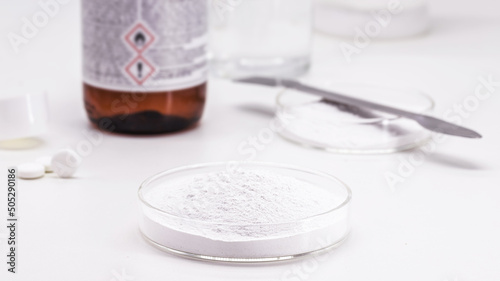 acetylsalicylic acid in the laboratory, petri dish with chemical components salicylic acid and acetic anhydride in the background photo