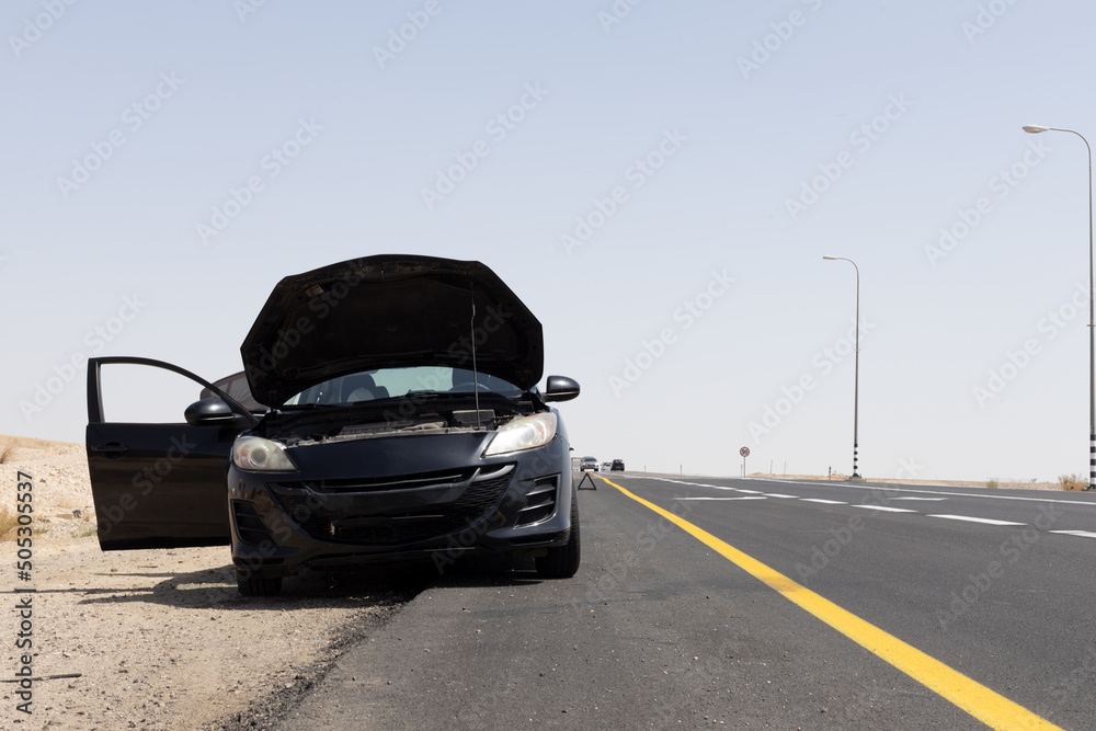 black car with open hood on the side of the road