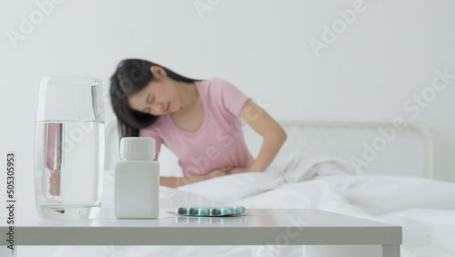 Young asian woman sitting on bed pain stomach or bowel with disease constipation or indigestion in bedroom at home, unhappy female sick and menstruation and stomachache, medical and health concept. photo