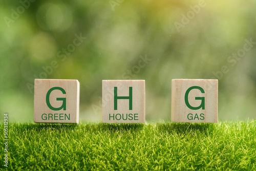 Business and GHG concept. Copy space. Greenhouse gas symbol. Concept words 'GHG, greenhouse gas' on cubes and blocks on a beautiful green background. photo