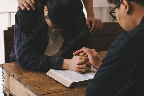 Christian young man praying for his friends while sitting on wooden chair at church prayer room. online group worship, World Day of Prayer, international day of prayer, hope, gratitude.