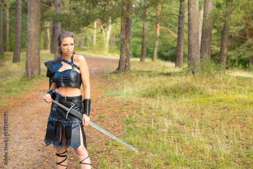 swordswoman wearing leather armor with sword patrols the wooden road