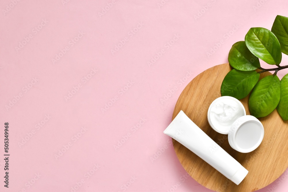 Φωτογραφία Natural cosmetics, skincare product - cream, lotion and micellar water on wood board on a pink background with green leaves plant