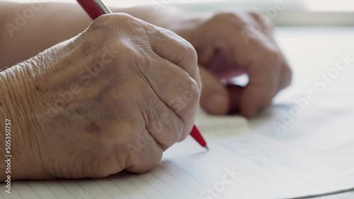 hand of an old woman writes a text in a notebook