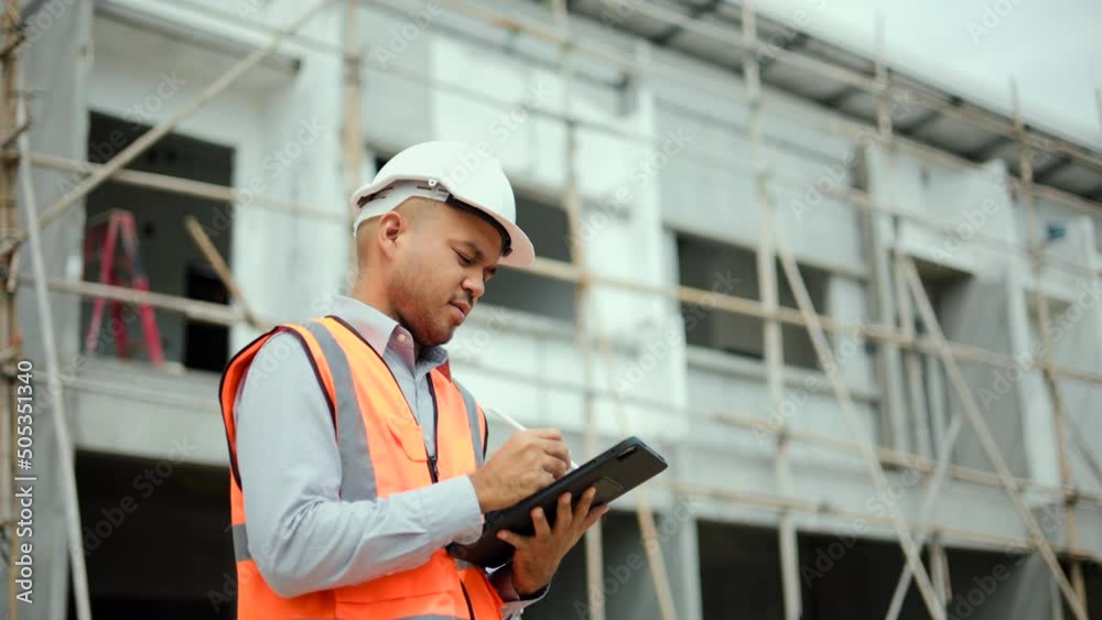 Confident asian engineer man Using tablet for checking and maintenance to inspection at modern home building construction. Architect looking forward with white safety helmet in construction site Confident asian engineer man Using tablet for checking and maintenance to inspection at modern home building construction. Architect looking forward with white safety helmet in construction site