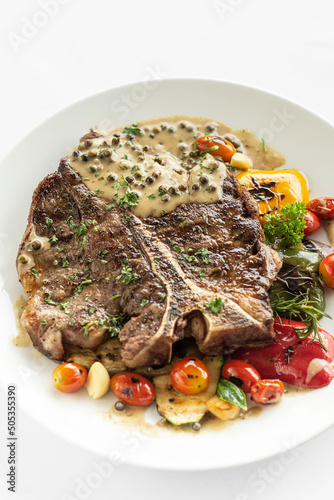 grilled t-bone steak with peppercorn sauce and vegetables