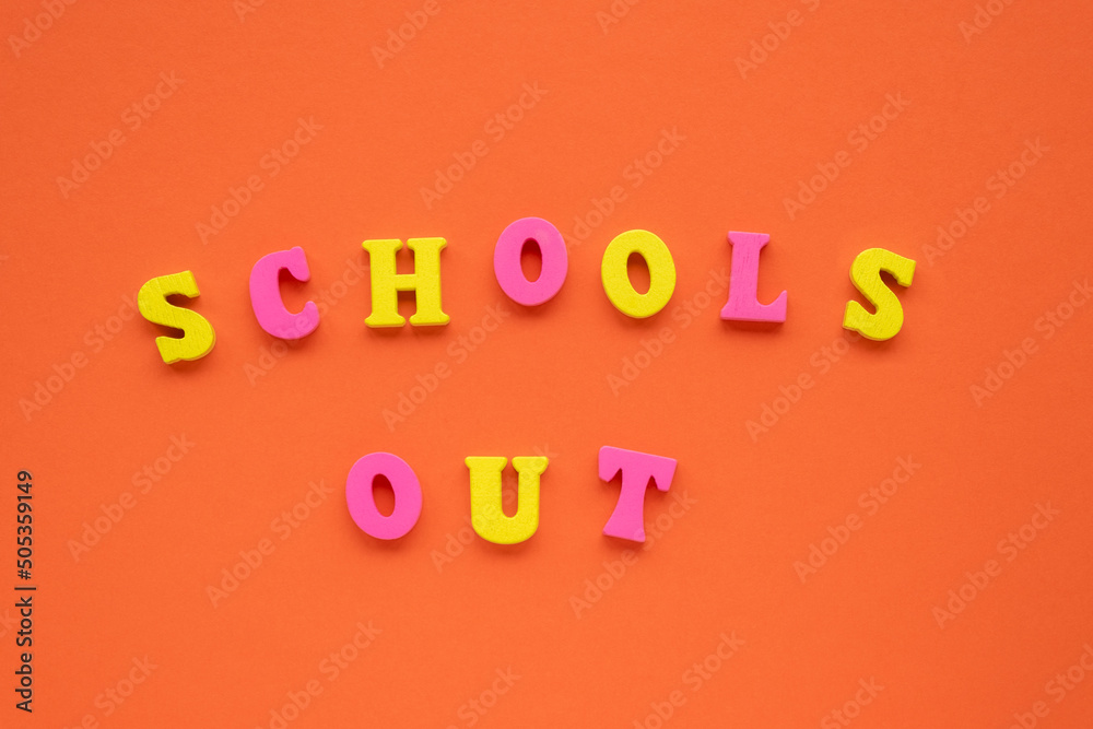 Light, vivid orange paper background. Yellow and pink wooden letters make School's out inscription. School's out concept. Top view, flat lay, copy space. Light, vivid orange paper background. Yellow and pink wooden letters make School's out inscription. School's out concept. Top view, flat lay, copy space.