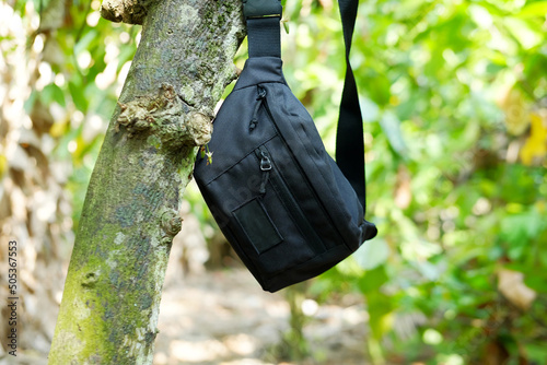 Men's black waist bag hanging on the tree
