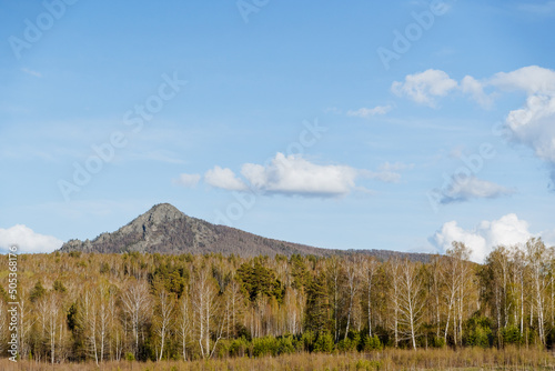 The ancient volcano is a cone-shaped mountain, a mountain landscape, the nature of Russia Bashkortostan, Mount Arvyakryaz Southern Urals, forest, blue sky, spring weather.