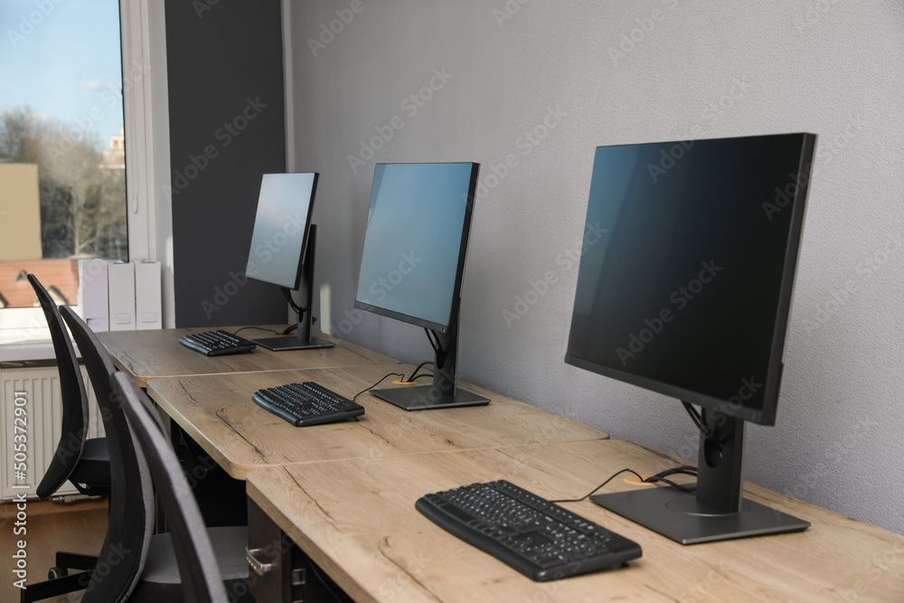 Open office interior. Modern workplaces with computers near light grey wall Open office interior. Modern workplaces with computers near light grey wall
