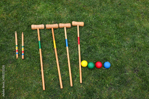 Set of croquet equipment on green grass, flat lay photo