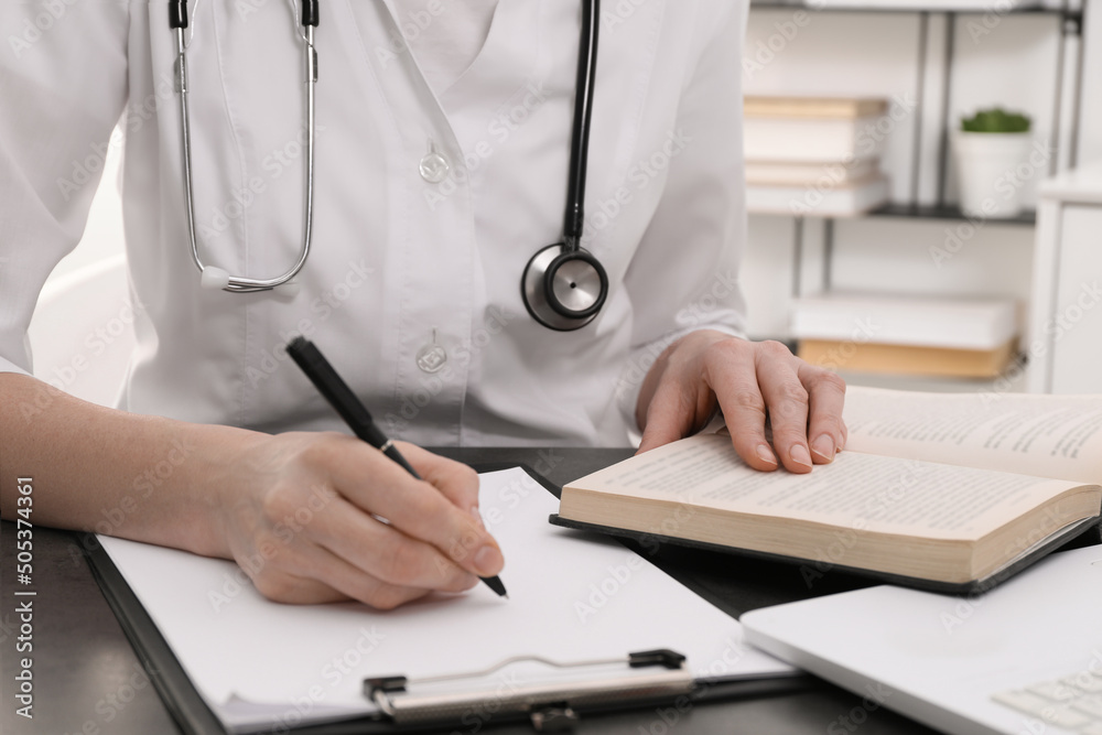 Medical student in uniform studying at table indoors, closeup Medical student in uniform studying at table indoors, closeup
