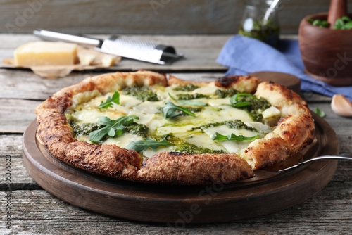 Delicious pizza with pesto, cheese and arugula on wooden table