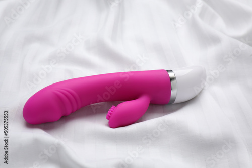 Pink vibrator on white fabric. Sex toy photo