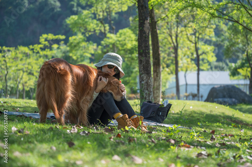 Golden Retriever accompanies its owner to sit on the grass in the park © chendongshan