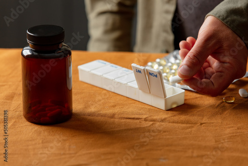 Εκτύπωση καμβά man sorts pills by day of the week in a sorter